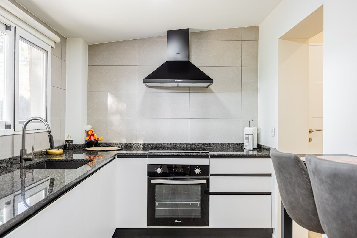 Modern kitchen with black countertops and stainless steel appliances.