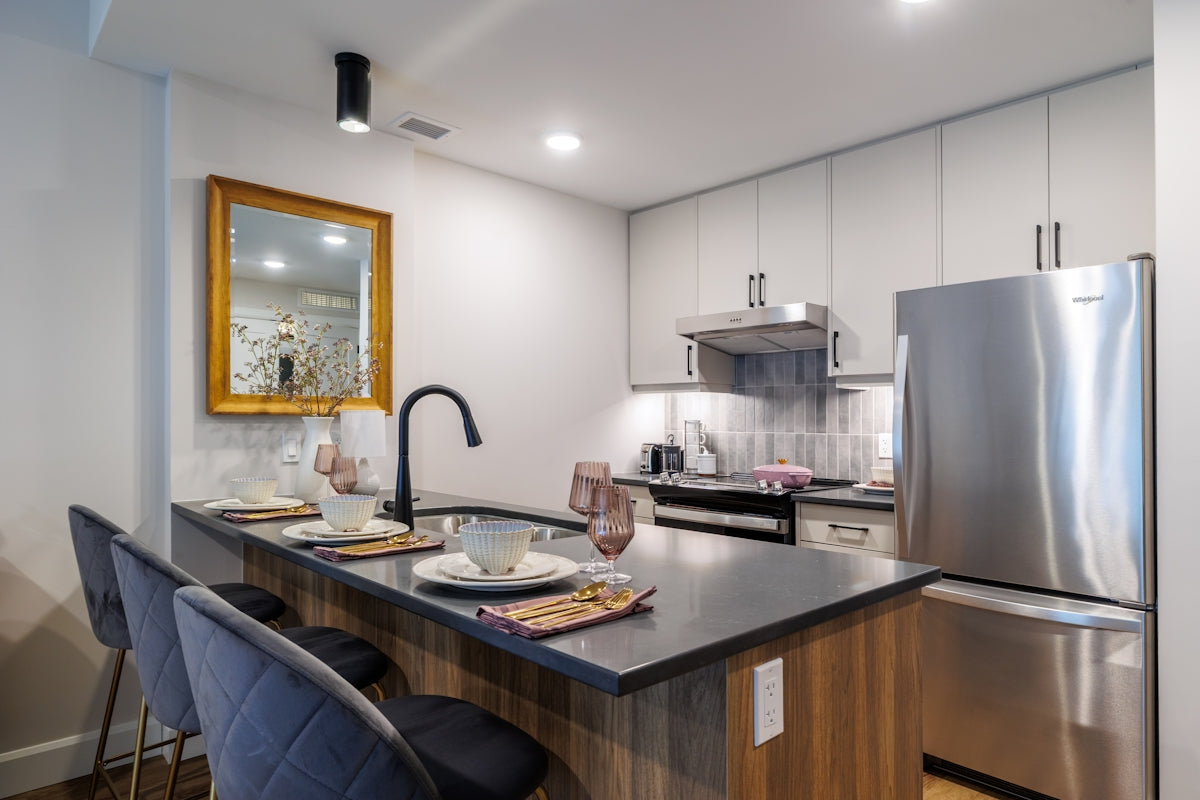 Modern kitchen island with bar stools and appliances.