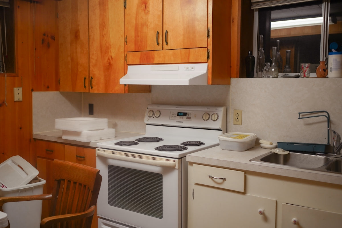A simple kitchen with wooden cabinets and white appliances.