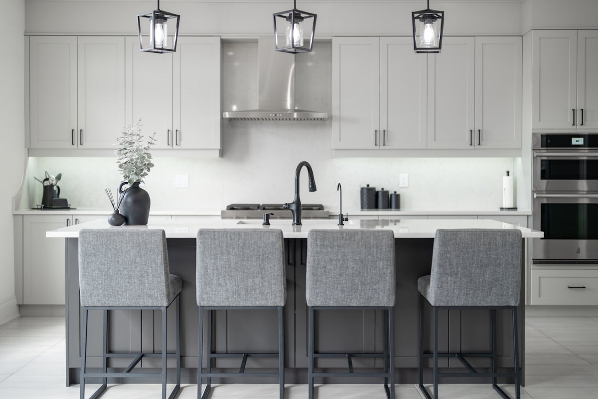 Modern kitchen island with four grey bar stools.