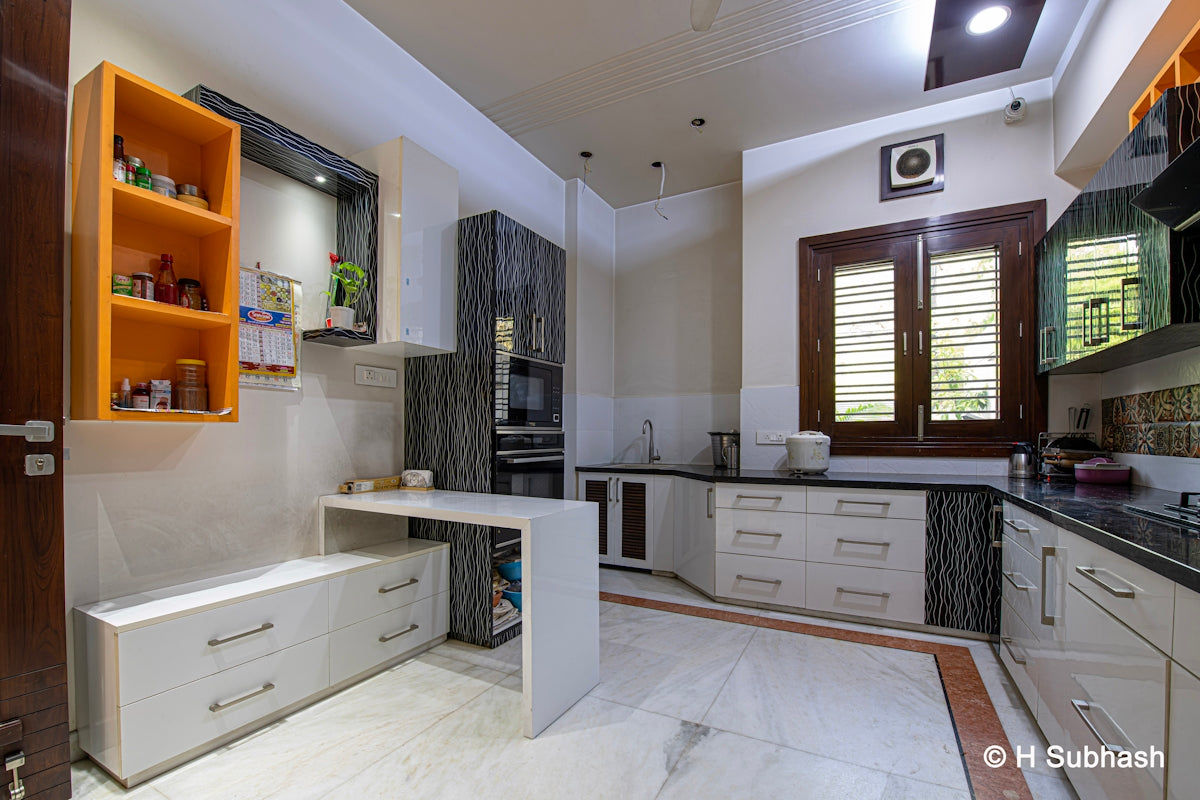Modern kitchen with white cabinets and orange shelves.